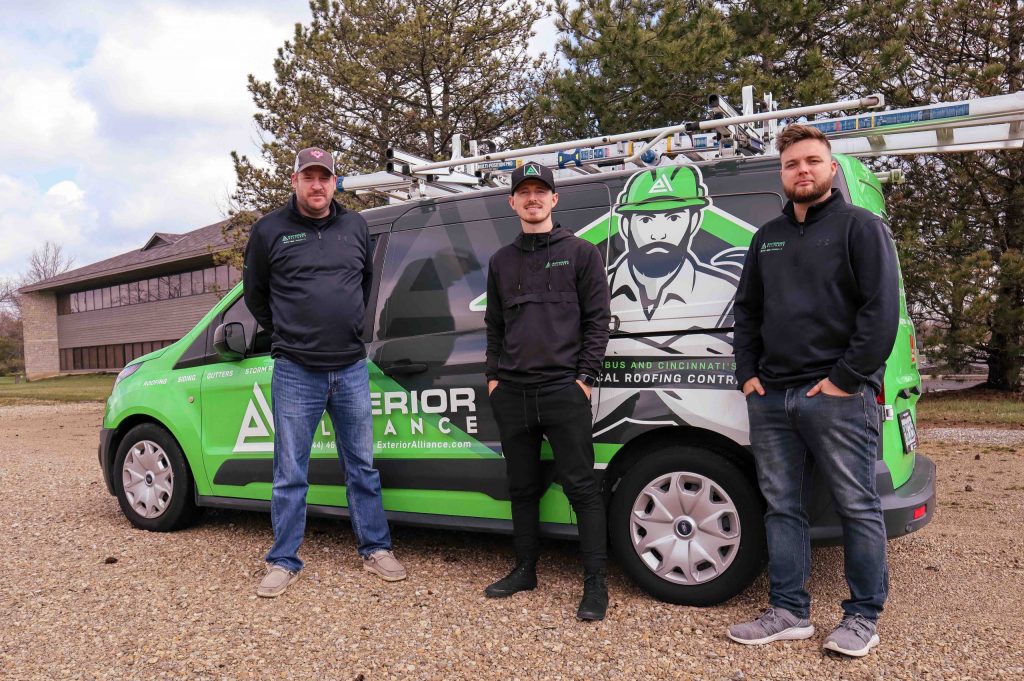 Three exterior alliance contractors are standing beside a branded service van with graphics, possibly representing a roofing company.